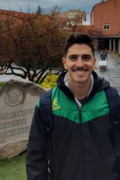 Foto de alumno destacado del ciclo TSEAS grado superior en Málaga, posando junto a una placa de la Facultad de Ciencias de la Educación del Deporte de Granada.