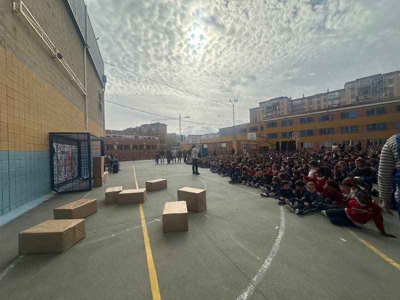 Alumnos del colegio reunidos en el patio celebrando el Día de la Paz escolar con un muro de cajas.