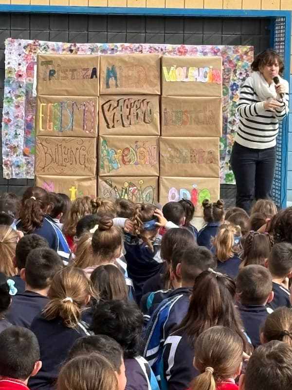 Profesora explicando la dinámica del muro de las palabras negativas a los alumnos en el Día de la Paz.