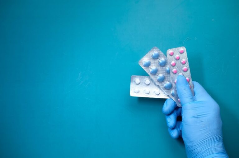 Mano con guantes de látex manipulando blísters de pastillas como parte de la formación en farmacia y parafarmacia en Málaga.