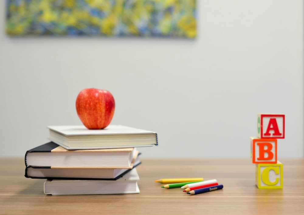 Material escolar y libros sobre un escritorio representando la sección trabaja con nosotros colegio en Málaga.